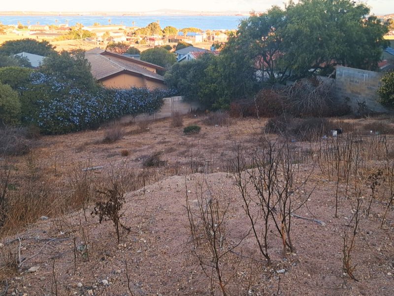 A sloped residential vacant plot offering elevated views of the surrounding neighborhood and distant coastline.
