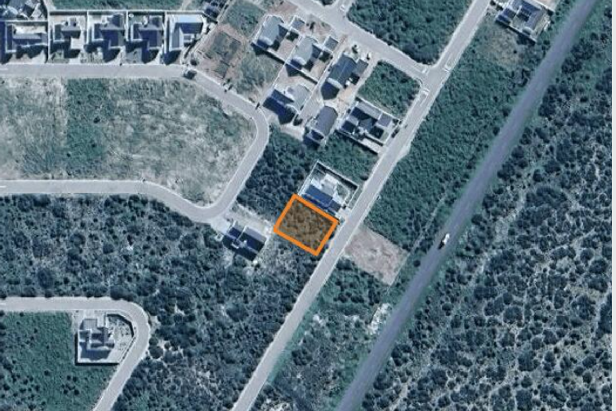 An aerial view of a vacant residential land plot situated within a developed suburban estate.