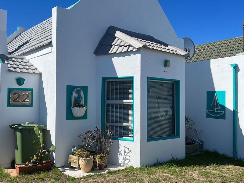 Front facade of a white cottage-style house featuring teal trim, tiled roofing, and aluminium window frames.
