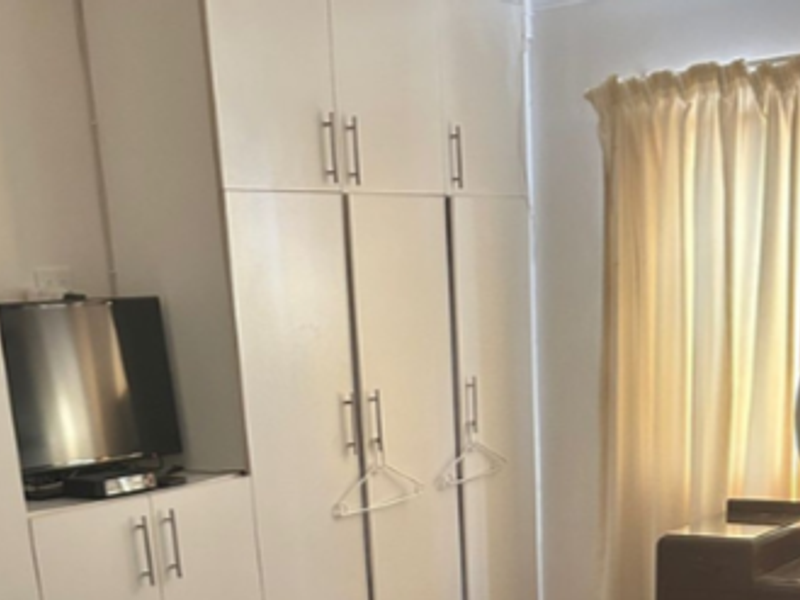 A bedroom featuring white built-in cupboards with modern handles, providing ample storage space.