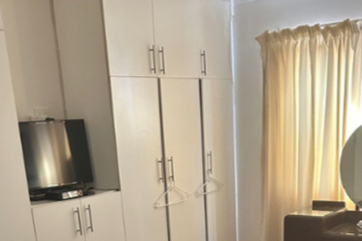 A bedroom featuring white built-in cupboards with modern handles, providing ample storage space.