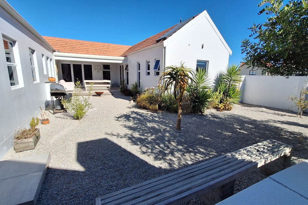 A well-maintained rear courtyard featuring gravel landscaping, established plants, and direct access to the home via sliding doors.