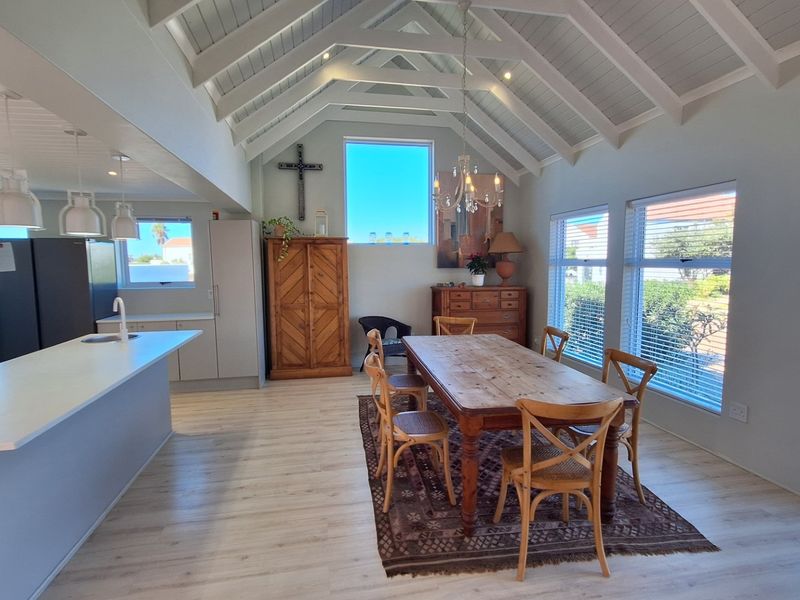 Spacious open-plan living and dining area featuring a high vaulted ceiling with exposed rafters, modern kitchen island, and abundant natural light.