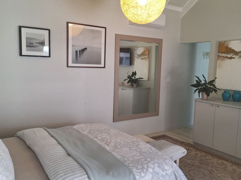 A well-maintained bedroom featuring a vaulted ceiling, split-system air conditioning, and integrated built-in cabinetry for storage.