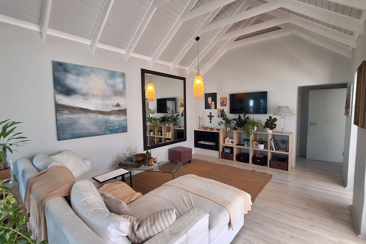 Spacious living room featuring a high vaulted ceiling with exposed white rafters, laminate flooring, and a modern built-in fireplace.