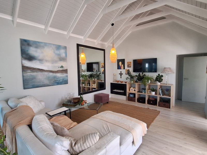 Spacious living room featuring a high vaulted ceiling with exposed white rafters, laminate flooring, and a modern built-in fireplace.