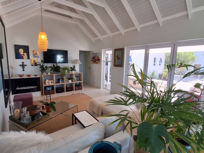 Bright living room featuring a high vaulted ceiling with exposed rafters, a built-in fireplace, and large bi-fold doors opening to the outdoor area.