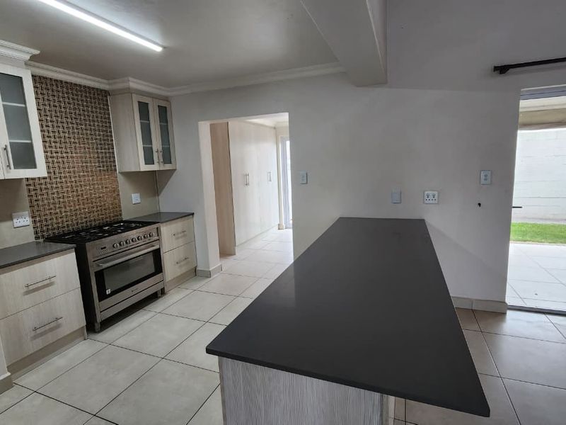Modern kitchen featuring light wood cabinetry, stone countertops, a gas stove, and a breakfast island, with direct access to an outdoor patio area.