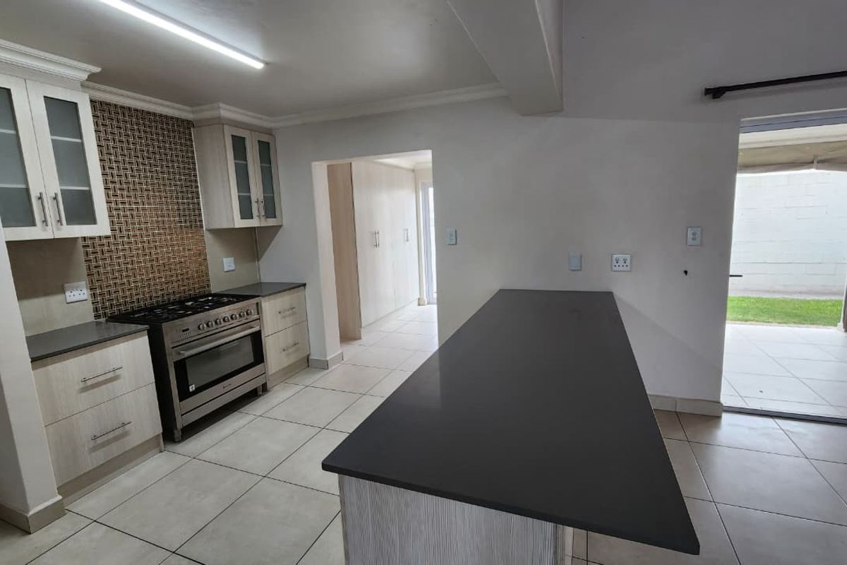 Modern kitchen featuring light wood cabinetry, stone countertops, a gas stove, and a breakfast island, with direct access to an outdoor patio area.