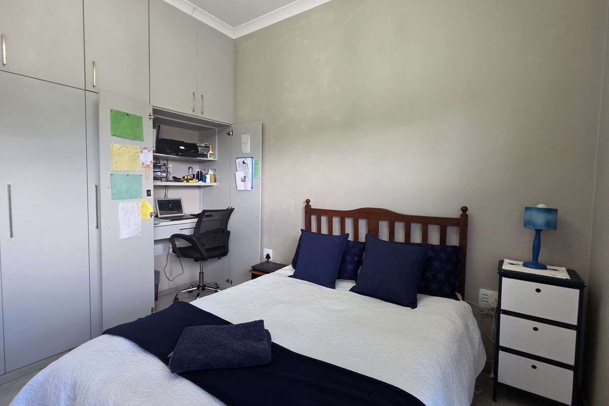 A functional bedroom featuring extensive built-in cupboards and a cleverly integrated desk space within the cabinetry.