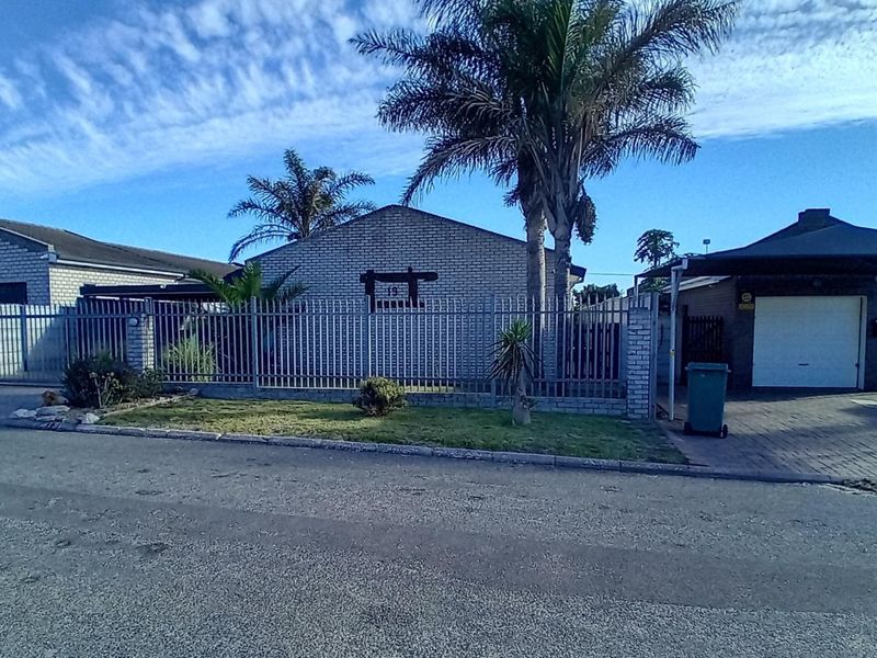 Front view of a residential property featuring a brick facade, metal security fencing, a paved driveway, and a covered carport.