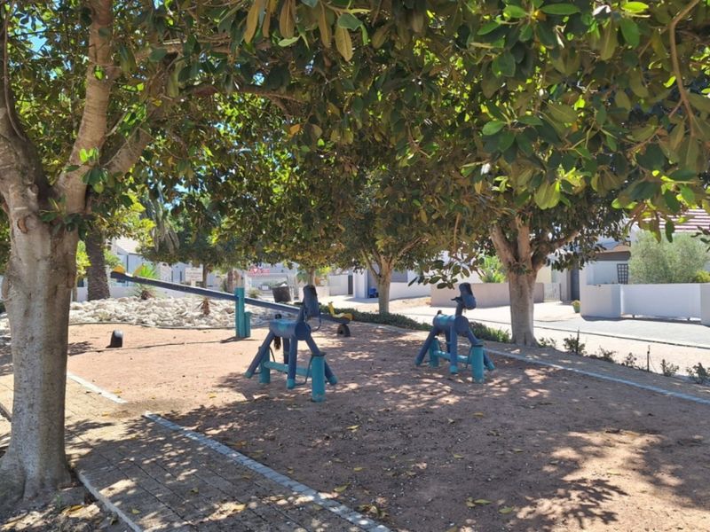 A landscaped garden area featuring mature trees, gravel ground cover, and paved edging, providing a shaded outdoor space.