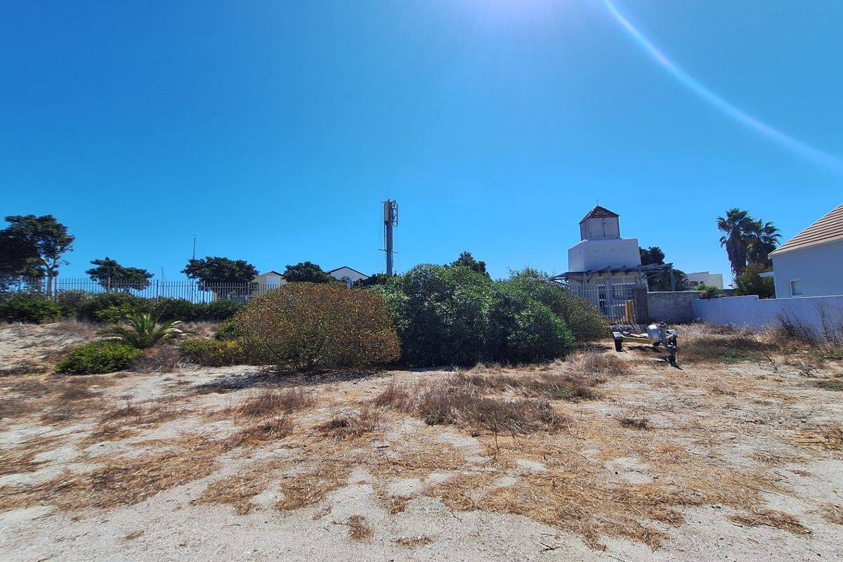 A view of the rear portion of the vacant residential land, featuring boundary fencing, a telecommunications mast, and natural ground cover.