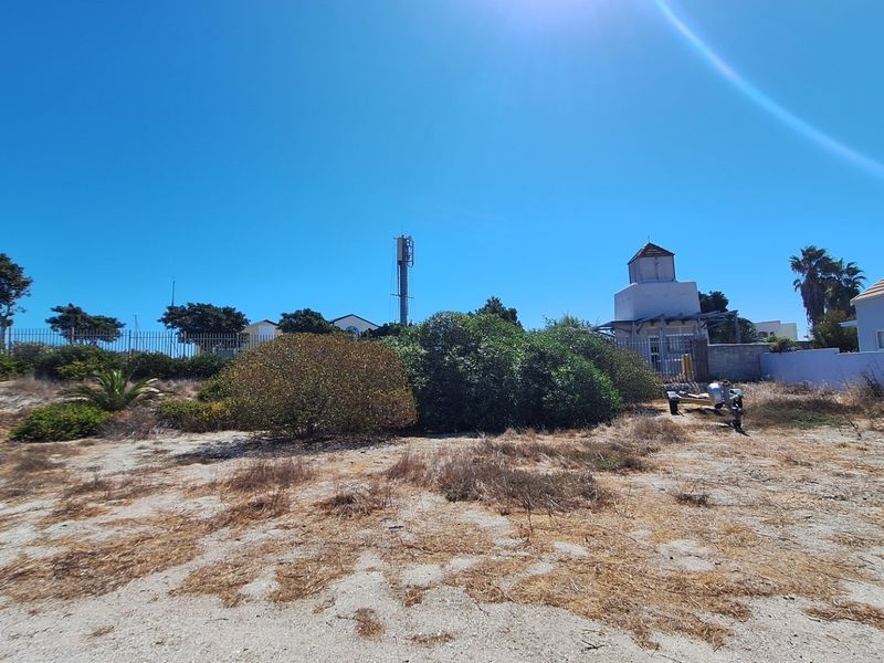 A view of the rear portion of the vacant residential land, featuring boundary fencing, a telecommunications mast, and natural ground cover.