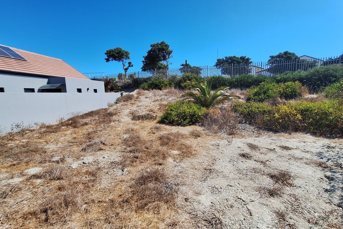 A view of the vacant residential land showing the rear boundary, perimeter fencing, and adjacent property structure.