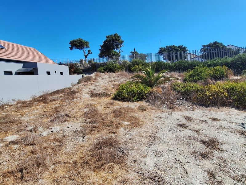A view of the vacant residential land showing the rear boundary, perimeter fencing, and adjacent property structure.