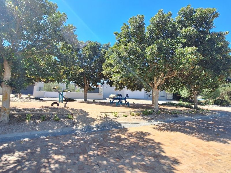 A well-maintained residential garden area featuring mature trees, a paved driveway, and a retaining wall, providing a pleasant outdoor space.