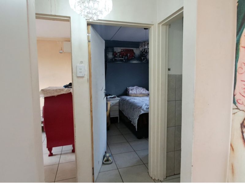A narrow hallway providing access to multiple rooms, featuring tiled flooring and standard door frames throughout the interior space.