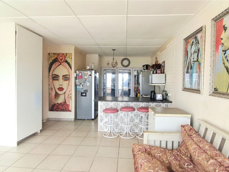 Open plan living and kitchen area featuring a breakfast bar, tiled flooring, and a drop ceiling, offering a functional layout for daily living.
