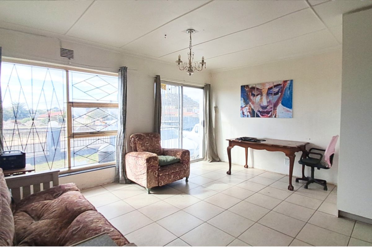 A living room featuring tiled flooring, a sliding glass door with security bars, and a ceiling light fixture, offering a functional space for renovation.