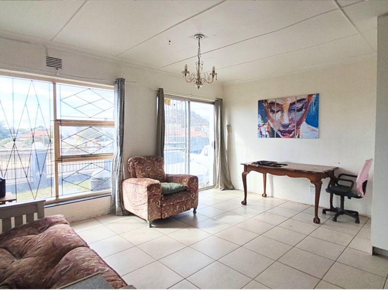A living room featuring tiled flooring, a sliding glass door with security bars, and a ceiling light fixture, offering a functional space for renovation.