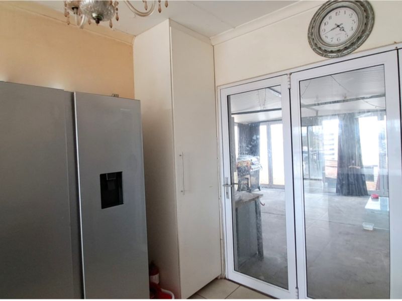 Kitchen area featuring a built-in pantry cupboard and glass sliding doors leading to an outdoor space.