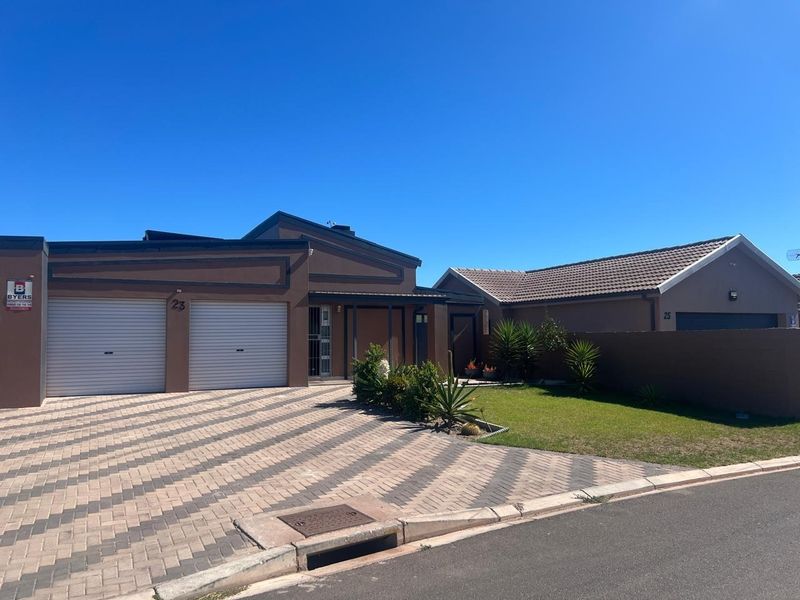 Front elevation of a modern house featuring a double garage, paved driveway, and a well-maintained front garden with boundary wall.