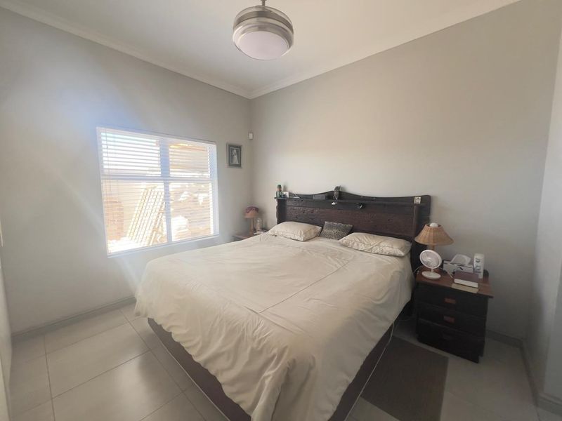 A bedroom featuring tiled flooring, neutral wall finishes, and a window with fitted blinds.