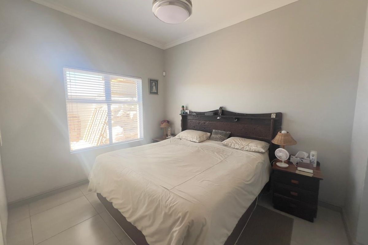 A bedroom featuring tiled flooring, neutral wall finishes, and a window with fitted blinds.