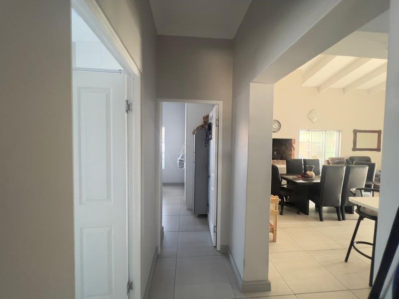 A bright, neutral-toned hallway featuring tiled flooring and clean lines, providing access to adjacent living areas and rooms.