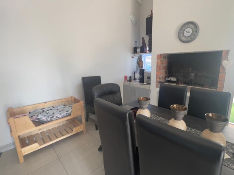 Dining area featuring tiled flooring and a built-in brick fireplace, providing a functional space for meals and gatherings.