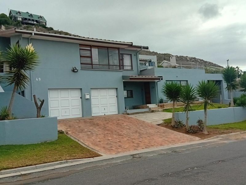 Front elevation of a two-story residential property featuring a double garage, brick paved driveway, and landscaped garden area.