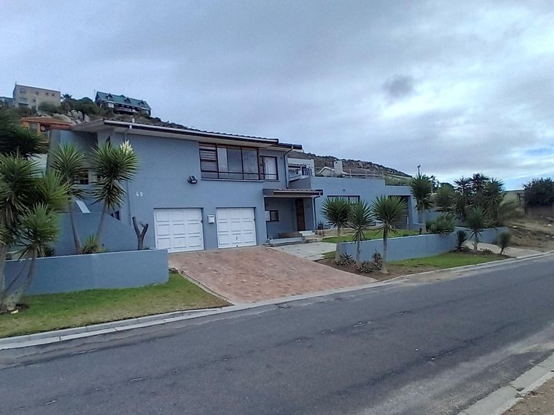 Front elevation of a multi-level residential property featuring a double garage, paved driveway, and elevated balcony area.