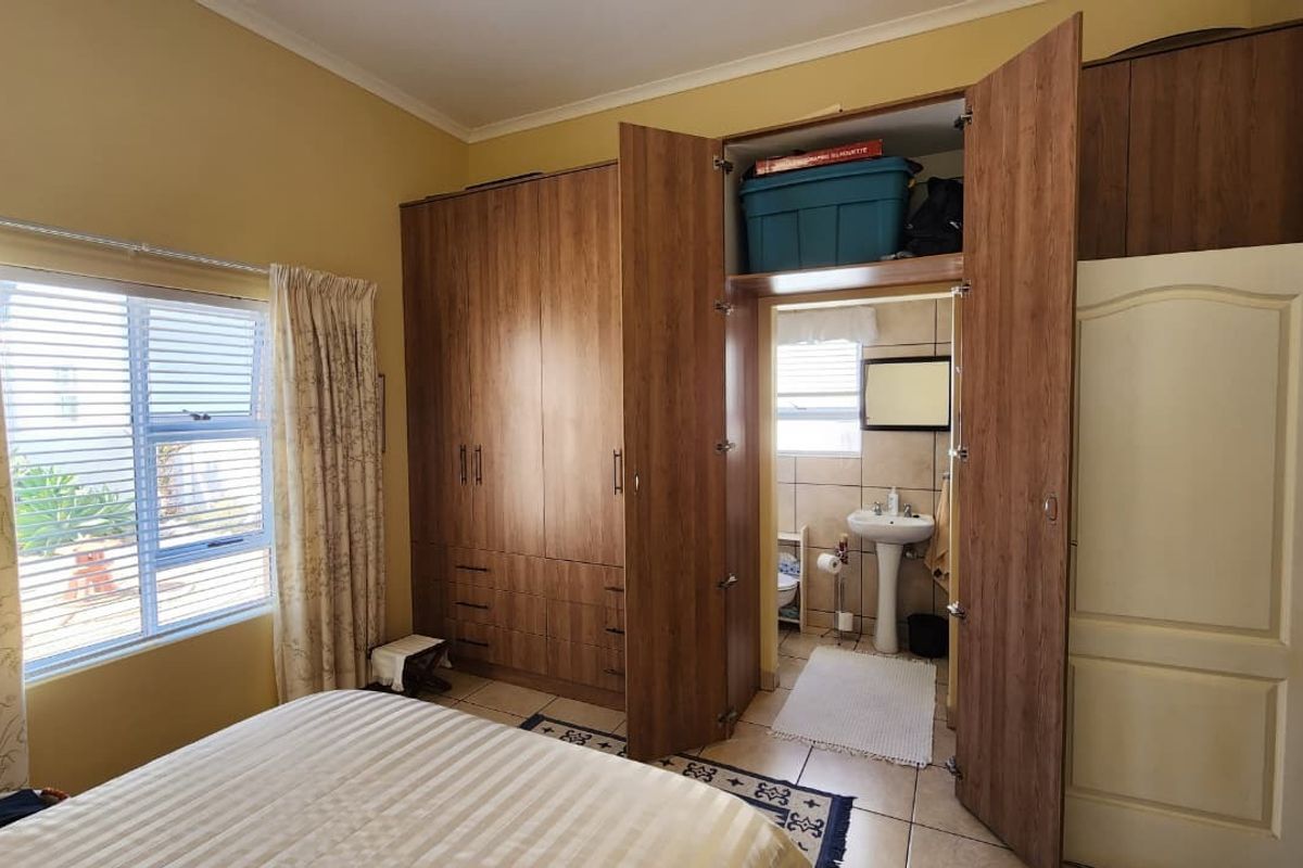 Bedroom featuring built-in wooden cupboards and an integrated en-suite bathroom with a pedestal basin and tiled flooring.