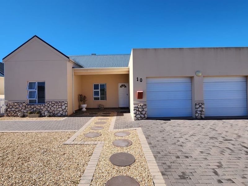 Front elevation of a single-story house featuring a double garage, stone cladding accents, paved driveway, and a covered entrance.