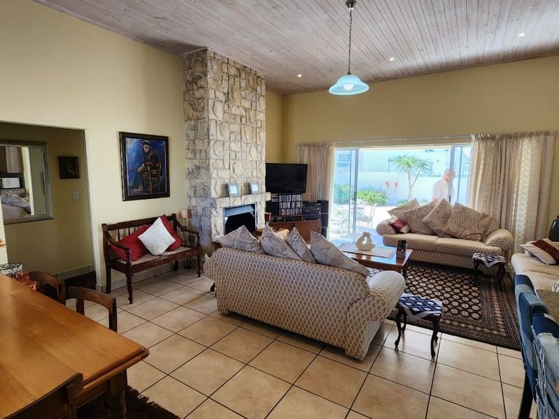 Spacious living room featuring a prominent stone fireplace, tiled flooring, and a timber-clad ceiling with direct access to the outdoor patio area.