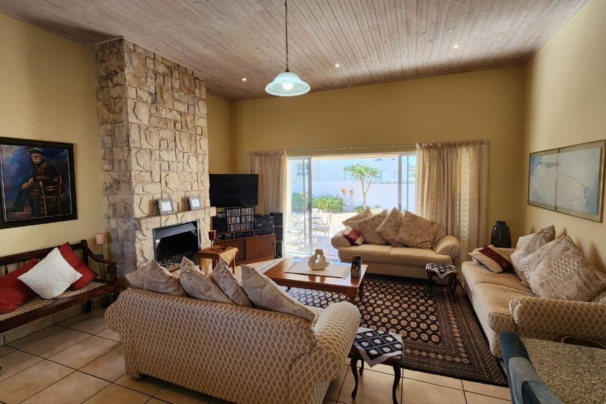 Spacious living room featuring a prominent stone fireplace, high wood-paneled ceilings, and large sliding doors providing access to the outdoor patio area.