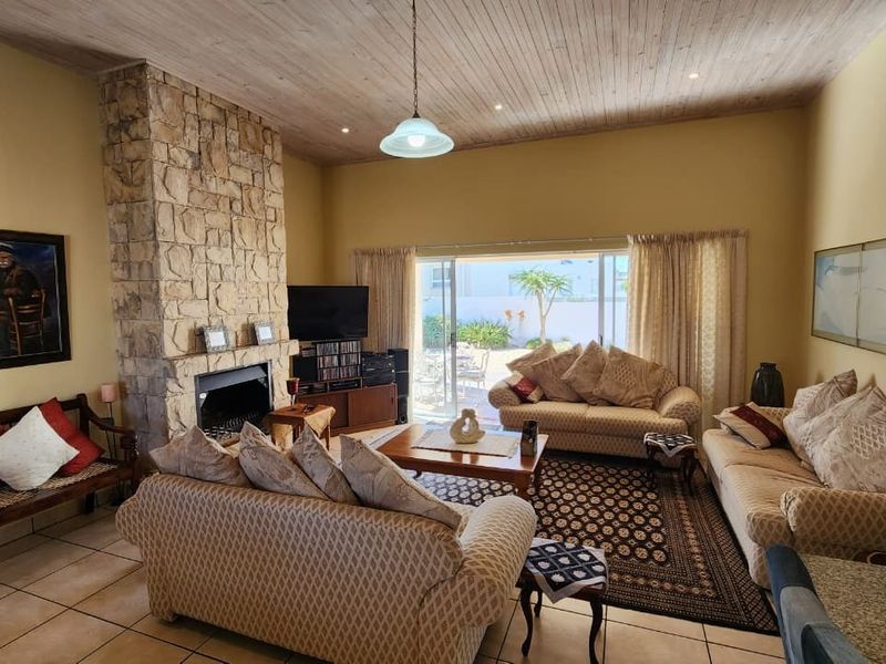 Spacious living room featuring a prominent stone fireplace, high wood-paneled ceilings, and large sliding doors providing access to the outdoor patio area.