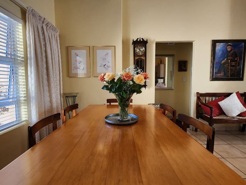 A dining room featuring tiled flooring, a stone-clad fireplace, and natural light from a large window.