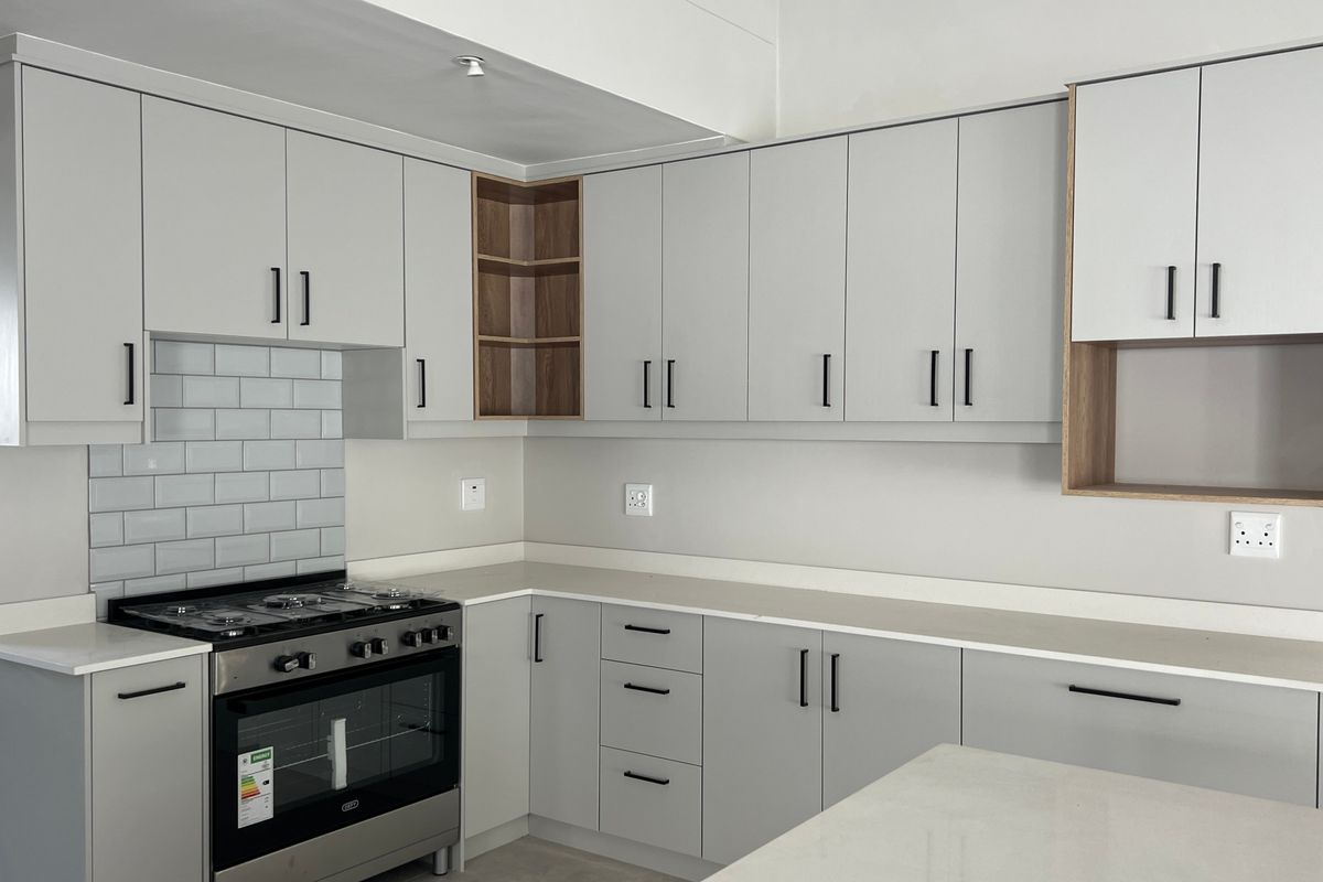 Modern kitchen featuring light grey cabinetry, quartz countertops, a subway tile backsplash, and a built-in gas stove with oven.