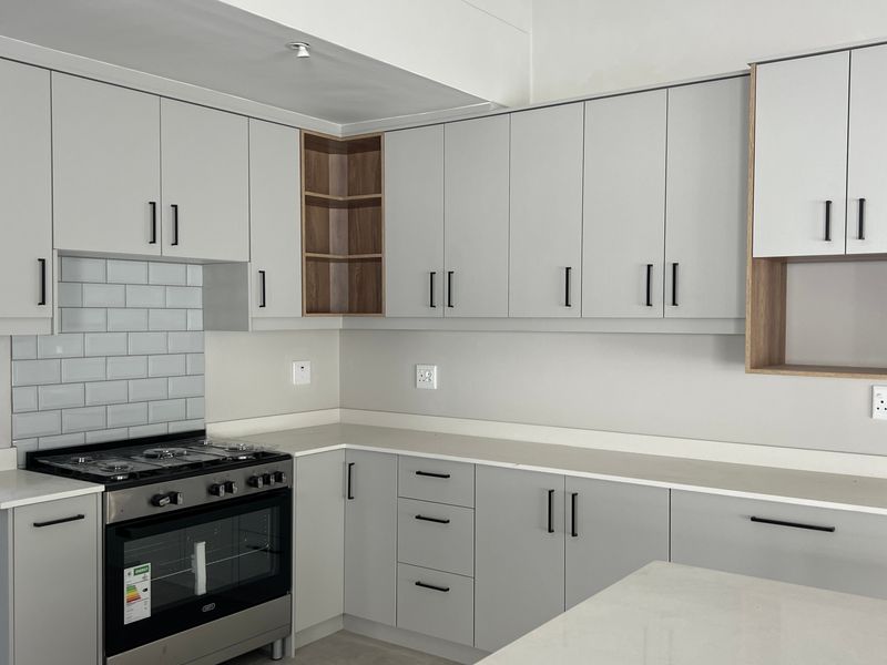 Modern kitchen featuring light grey cabinetry, quartz countertops, a subway tile backsplash, and a built-in gas stove with oven.