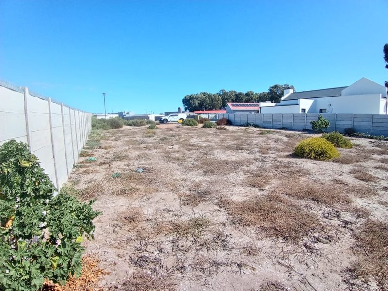 A vacant residential plot featuring sandy ground and enclosed by precast concrete boundary walls.