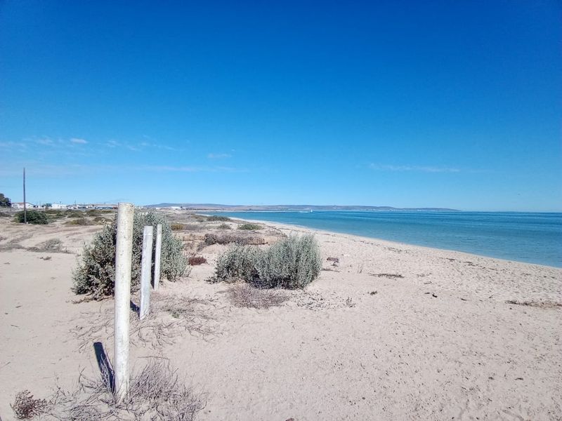 A scenic view of the sandy coastline and ocean, showcasing the natural beauty and direct water access of this vacant residential land.
