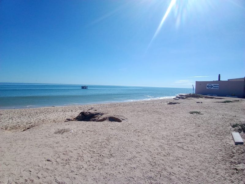A scenic view of the sandy beach and ocean, highlighting the property's direct coastal access and prime waterfront location.