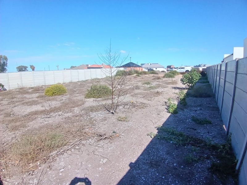 A vacant residential plot featuring a level surface enclosed by precast concrete boundary walls, ready for development.