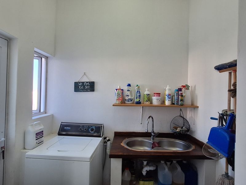 Functional laundry area featuring a double bowl sink, wooden countertop, wall-mounted shelving, and direct access to the exterior.