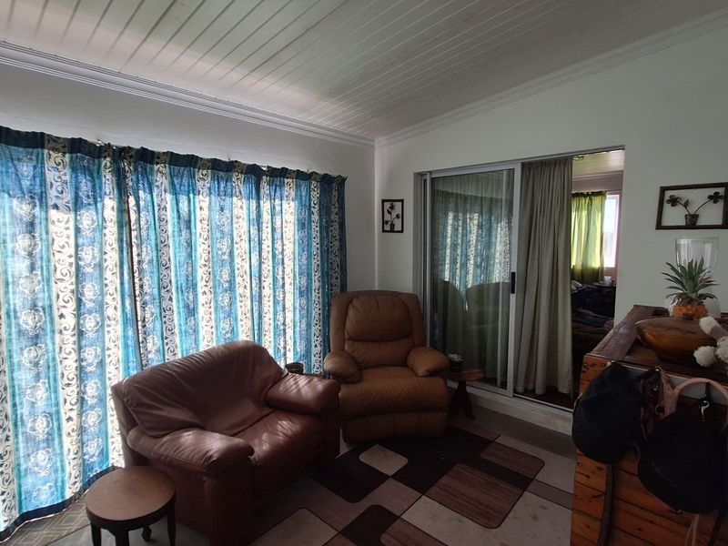 A living room featuring a sliding glass door leading to an adjacent space, finished with a white tongue and groove ceiling.