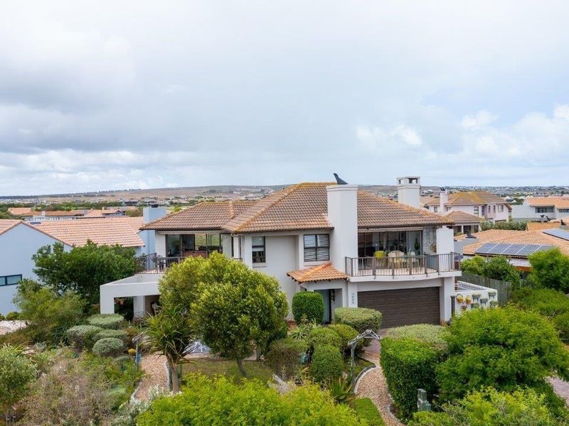 Aerial view of a multi-level residential property featuring a tiled roof, balcony, attached garage, and established landscaped garden in a suburban setting.