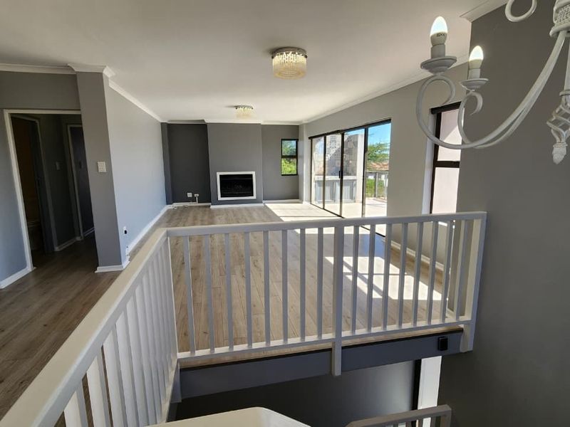 Spacious open-plan living area featuring modern laminate flooring, a built-in fireplace, and large sliding doors leading to an outdoor balcony.