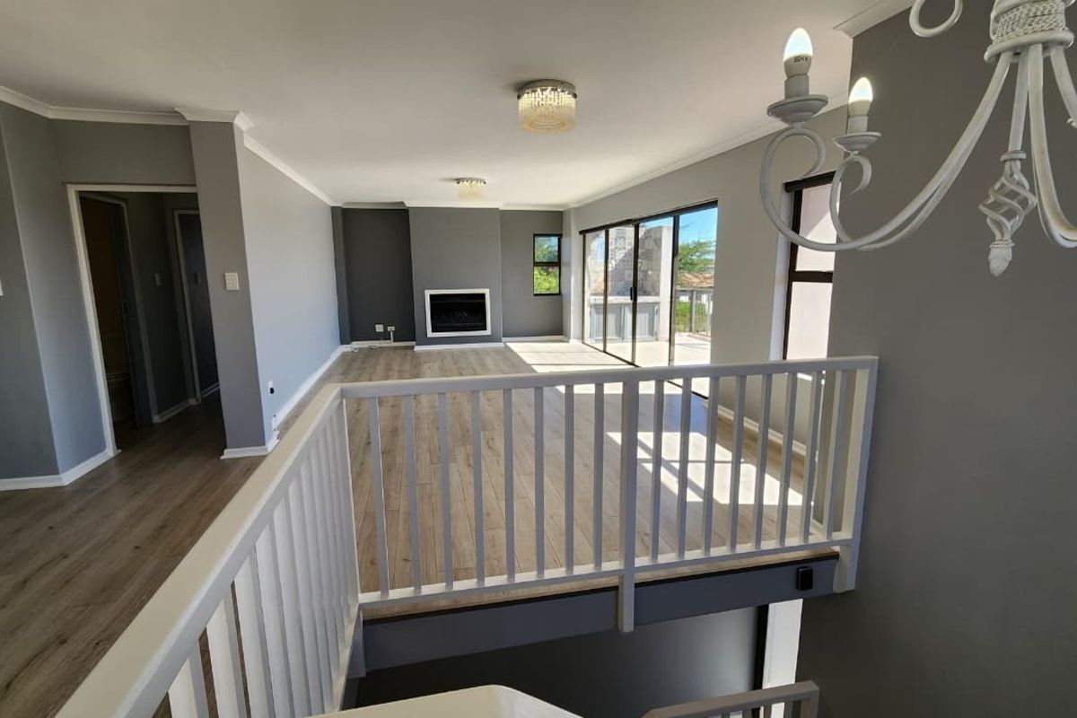 Spacious open-plan living area featuring modern laminate flooring, a built-in fireplace, and large sliding doors leading to an outdoor balcony.